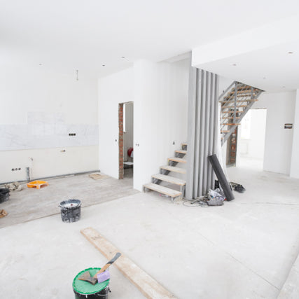 Contractor RentalsA bright, unfinished interior with white walls and concrete floors, scattered construction tools, and a staircase. The atmosphere feels open and in-progress.